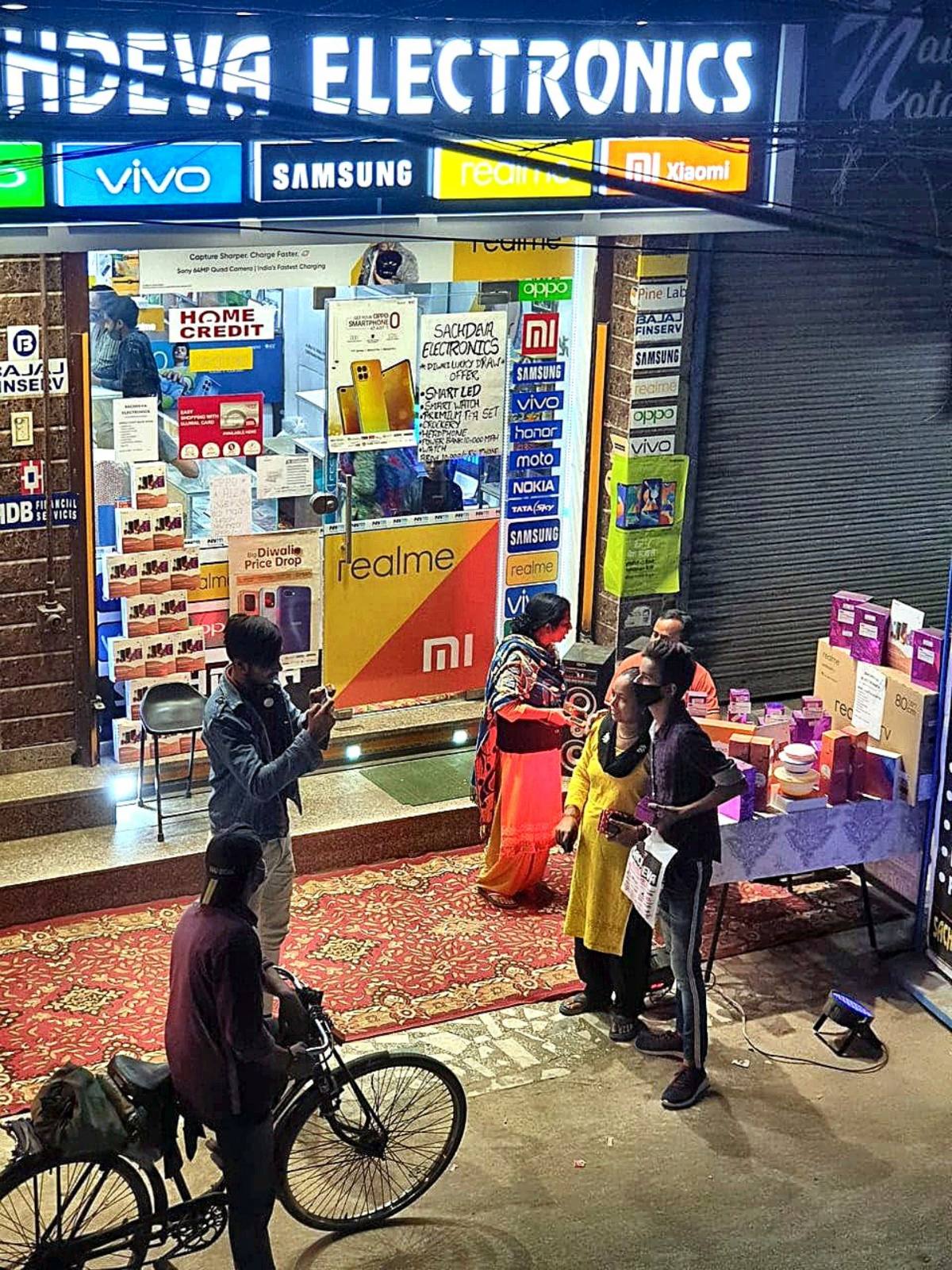 Sachdeva Electronics shopfront at night with customers
